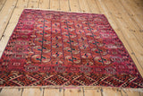 High angle view of a square antique Turkmen rug, showing its wine red gul pattern and geometric borders.
