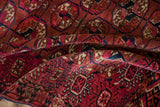The rich texture and geometric gul pattern of a draped antique Turkmen rug in burgundy and navy blue.