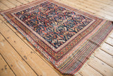 Angled view of an antique Afshar rug's serrated leaf motif and colorful plain weave end.