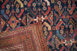 A folded corner of an antique Afshar rug reveals the hand-knotted pile and original plain weave foundation.
