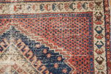 Worn madder red field with navy pinwheel motifs and ivory simplistic plant border.