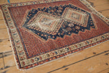 Corner of vintage Afshar rug, showing beige germinating plant border and madder root red field with tattered edge.