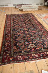 Vintage Malayer rug seen from an angle, displaying a covered field of gem-toned floral motifs.