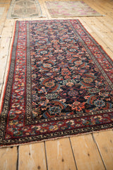 Angled view of a vintage Malayer rug showing its allover pattern and colorful serpent motif border.