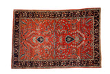 Vintage Sarouk rug with a dense, polychromatic floral design on a brick red field and a dark navy border.