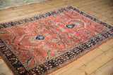 Angled view of a vintage Sarouk rug's expressive floral vines on a rich brick-red field.