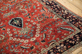 Vintage Sarouk rug detail showing polychromatic leaves and vines against a dark navy blue border.