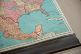 Vintage Nystrom map's worn bottom edge, dark wooden dowel, and Caribbean islands detail.