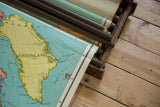 Vintage Nystrom pull down map detail, Greenland's yellow land, teal water, partially rolled.