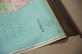 Partially rolled vintage Nystrom map showing light blue ocean and dark wooden dowel.