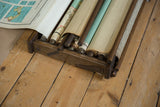 Rolled light blue and beige maps visible inside the vintage wooden rack.