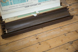 Textured dark brown roller and aged wood frame of the vintage map rack.