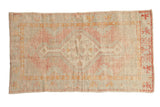 Vintage distressed Oushak rug with a floral medallion in soft pink, seafoam, and saffron yellow.