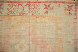 Worn texture of a vintage Oushak rug's blossom border in faded seafoam green, pink, and saffron yellow.