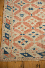 Distressed pile texture with terracotta diamonds, blue guls, and intact Dosemealti rug selvage.