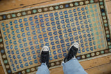Distressed Oushak rug with dusty gold field, royal blue and mint floral patterns, visible abrash.