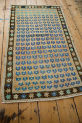 Distressed vintage Oushak rug with blue floral field and starburst border detail.