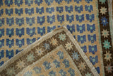 Folded vintage distressed Oushak rug, revealing reverse, fringe, and worn blue and gold floral pattern.