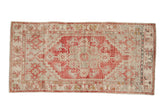 Vintage distressed Oushak runner with a raspberry red stepped medallion on a silver and ivory field.