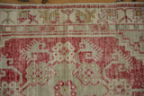A close-up of the distressed Oushak runner's germinating plant border in raspberry red and dusty gold.