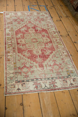 Angled view of a distressed Oushak runner with raspberry red and platinum geometric patterns.