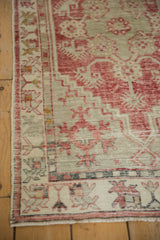 Corner view of the distressed Oushak rug's floral border and time-softened texture.