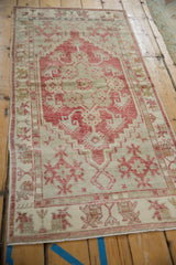 Angled view of the vintage Oushak runner's stepped medallion in dusty raspberry red and beige.