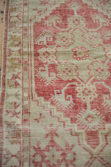 The low, worn pile and stepped geometric motifs of a distressed raspberry red Oushak rug.