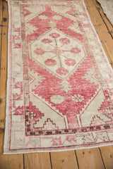 Faded raspberry and ivory floral and vine patterns with distressed pile on a vintage Oushak rug.