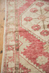 Distressed texture and side selvage of vintage Oushak runner, with faded raspberry red and beige.
