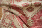Distressed Oushak rug's pile texture with faded raspberry and ivory floral pattern.