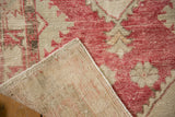 Folded vintage Oushak rug revealing hand-knotted construction and distressed raspberry red pile.