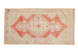 Vintage distressed Oushak rug with a faded red stepped medallion on a worn ivory and silver ground.