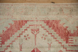 Evenly worn pile on a vintage Oushak rug showing faded cherry red and seafoam green stepped patterns.