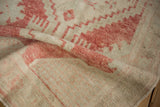 A folded corner of the distressed Oushak rug reveals its hand-knotted low pile and texture.