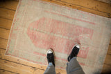 A person's view standing on a distressed vintage rug, highlighting its low-pile texture and scale.