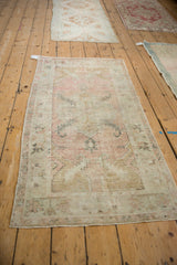 Vintage distressed Oushak runner laid out on the floor, seen from a high angle to show the full design.