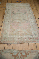 A distressed Oushak runner viewed lengthwise, highlighting its faded dusty rose and silver tones.