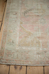 Hand-knotted texture of a distressed Oushak rug with time-softened dusty rose and silver pile.