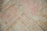 A folded corner reveals the distressed pile and hand-knotted foundation of a vintage Oushak rug.