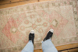 The soft, distressed texture of a vintage Oushak runner in dusty rose and olive green.