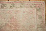 Corner of the distressed rug showing a floral vine border in dusty rose and olive.