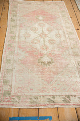 Angled perspective of a vintage Oushak runner's faded floral medallion and border.