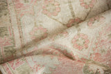 Detailed texture of a hand-knotted Oushak rug with time-softened rose and olive hues.