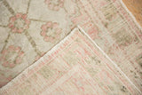 Corner view of a vintage Oushak rug, folded to display its hand-knotted foundation.