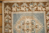 Oushak rug corner: dusty denim blue medallion, brown germinating plant border, and even wear.