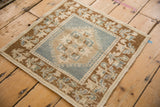 Distressed Oushak rug corner with copper germinating plant border, dusty denim blue floral field, and visible knot heads.