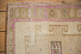 Corner of a Vintage Distressed Kars rug, showing faded magenta geometric border and worn hand-knotted pile.