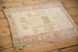 Distressed Kars rug corner with faded magenta floral border and beige geometric motifs.