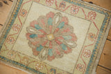 A vintage Oushak mat's scalloped medallion showing evenly worn pile in dusty lime and red.